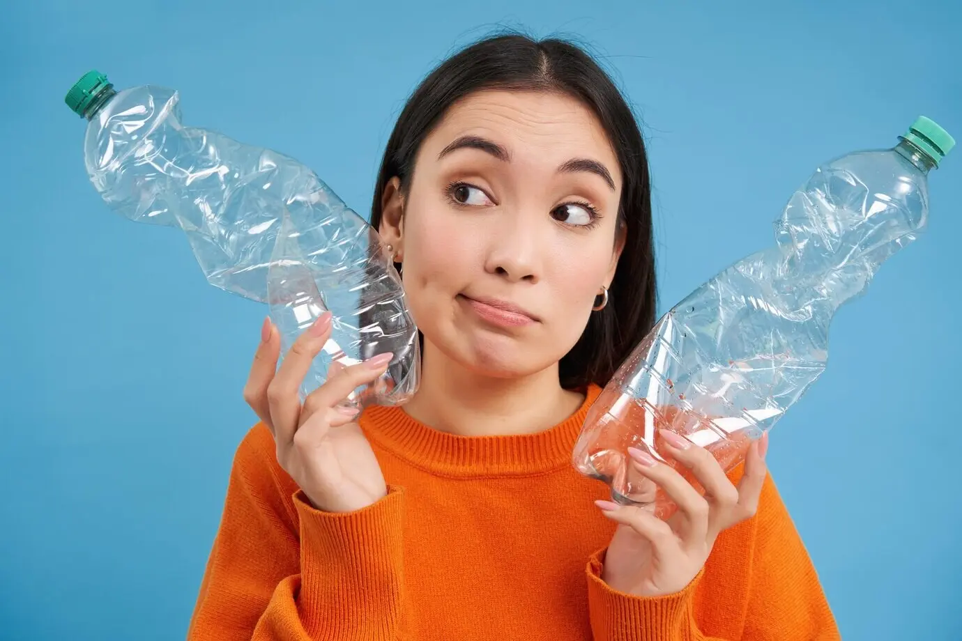 Ein Mädchen mit zwei Plastikflaschen denkt nach, blickt zur Seite, sortiert Müll und rettet den Planeten durch Recycling.